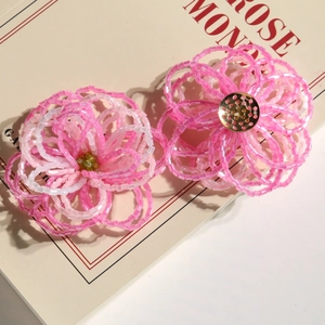 Macro view of handmade pink beaded gradient flower accessories on a cream book