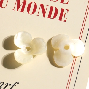 Dettaglio macro di perline a tulipano in acrilico bianco perla con foro per gioielli fai da te