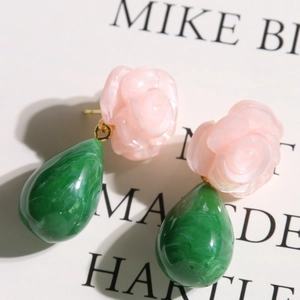 Détail d'une boucle d'oreille rose en résine avec perle marbrée verte et métal doré