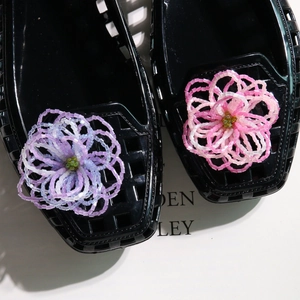 Close-up of black jelly flats featuring handcrafted gradient beaded flower charms on top