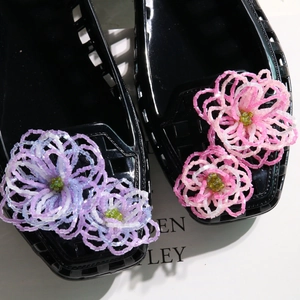 Detailed view of handmade beaded flowers in pink and purple on black jelly shoes