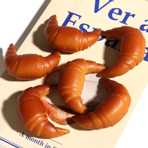 Cinque ciondoli a forma di croissant in resina con trama realistica su un libro