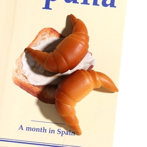Dettaglio macro di due croissant in resina realistici con texture dorata su rivista