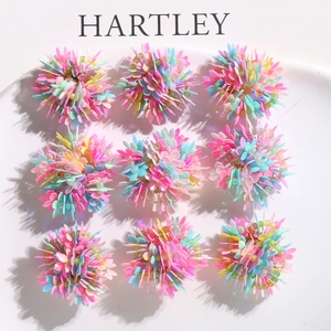 Macro shot of 9 colorful sequin DIY flower clusters arranged on a white ceramic plate
