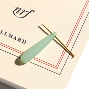 Detailed macro view of a translucent pale green teardrop pendant with gold metal pin