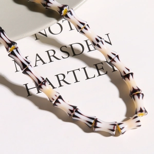 Close-up of handmade millefiori glass bamboo style beads with yellow cord detail