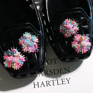 Macro detail of colorful sequin flower clusters on shiny black jelly sandal accessories