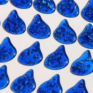 Macro view of blue teardrop resin charms with embedded foil for DIY jewelry making