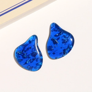 Macro view of irregular deep blue resin charms with sparkling silver foil flakes inside