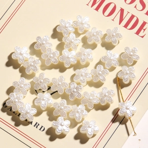Vintage pearl camellia flower charms for DIY jewelry making on a book background