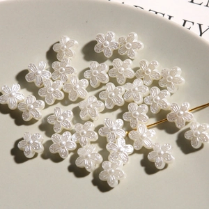 Macro shot of white resin flower charms with pearlescent finish for DIY jewelry making