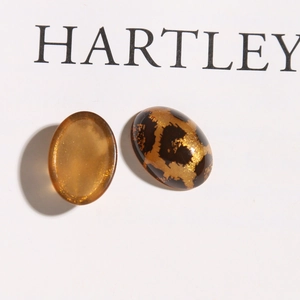 Macro-detail van ovale acryl cabochons met amber en glitter luipaardpatronen