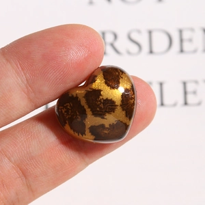 Macro-opname van een hartvormige acryl bedel met bruine luipaardprint en gouden glitters