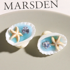 Primer plano de pendientes de concha con resina azul, estrella de mar y circón