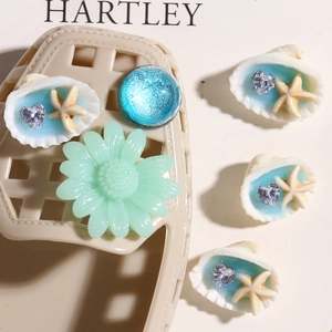 Detalle de dijes de conchas y estrellas de mar azules con cristales para zuecos