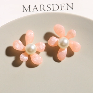 Close-up of pink translucent resin flower earrings with white pearls and glitter finish