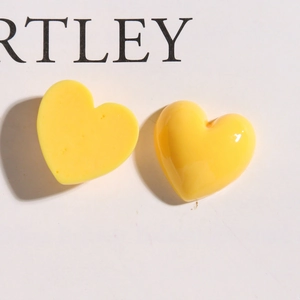 Vue macro de deux breloques cœur en résine jaune brillante pour accessoires de cheveux DIY