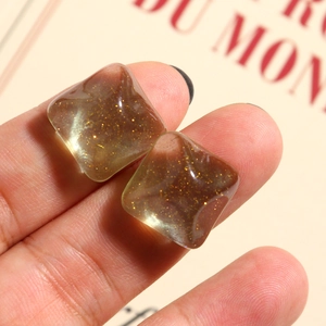 Macro detail of square avocado green resin studs with glitter and gold foil flakes