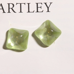 Macro shot of mint green square resin charms with gold glitter for DIY jewelry