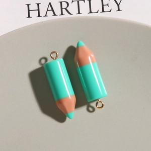 Macro view of mint green pencil-shaped resin pendants with golden metal rings