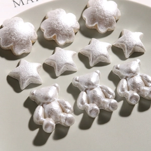 Macro detail of pearlescent DIY charms featuring flowers, stars, and bears for crafts