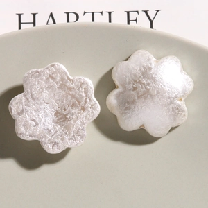 Macro view of white pearlescent flower charms with irregular texture on a ceramic plate