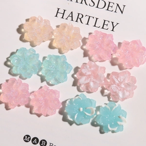 Detailed flat lay of glittery resin camellia flower charms for DIY hair accessories