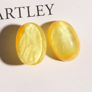 Macro view showing yellow glitter resin oval charms with smooth surface and pearlescent finish