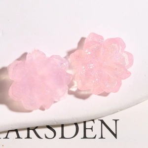 Macro shot of light pink cherry blossom resin charms with shimmering glitter finish