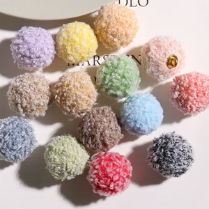 Flat lay of thirteen colorful curly plush pom poms with golden metal rings for DIY jewelry