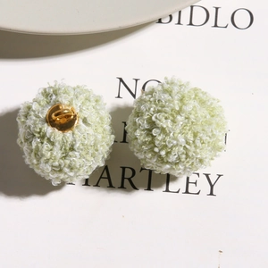 Macro shot of two light green plush pompom beads with golden metal loops for DIY jewelry
