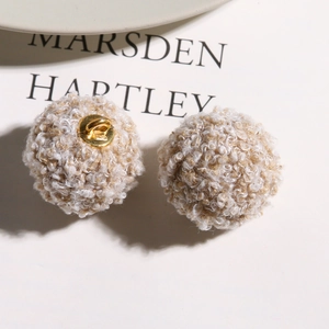 Close-up of mixed beige teddy fleece plush charms with golden metal shanks for DIY crafts
