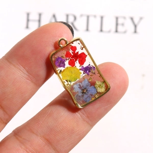 Macro detail of rectangle resin pendant with dried flowers and gold foil elements