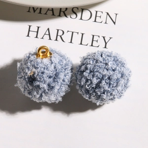 Detail shot of blue curly faux teddy fur pompom pendants for DIY jewelry with gold metal loop