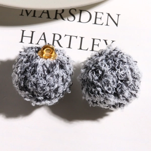 Close-up of curly plush teddy wool charms with gold metal rings for DIY jewelry making