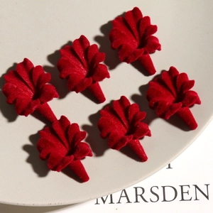 Close-up of deep red velvet trumpet flower charms on a ceramic plate for DIY jewelry
