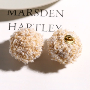 Close-up of curly faux teddy fur charms in cream and coffee tones for DIY jewelry crafts