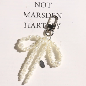 Detailed view of pearl bow charm with silver lobster clasp for shoe and bag decoration