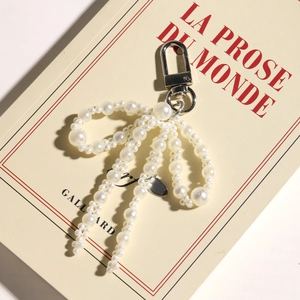 Elegant pearl bow keychain with silver clasp on vintage book background