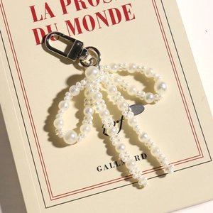 Macro detail of a pearl bow pendant with silver clasp on a vintage book cover
