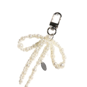 Elegant white pearl bow charm with silver lobster clasp and oval metal tag
