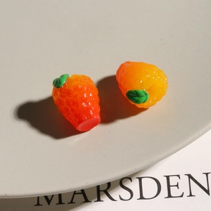 Nahaufnahme von orangefarbenen Himbeer-Anhängern aus Harz für DIY-Schmuckherstellung