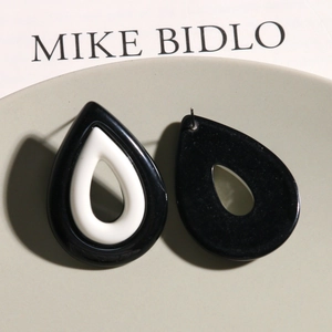 Detalle de pendientes de resina bicolor en forma de gota con diseño blanco y negro