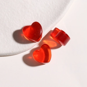 Detailed view of red heart resin charms with gold glitter and glossy finish for DIY