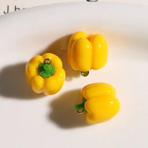 Detailed view of three small resin yellow bell pepper charms with metal loops for DIY jewelry