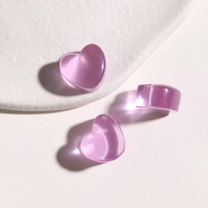 Macro shot of three purple translucent heart-shaped resin charms with subtle glitter