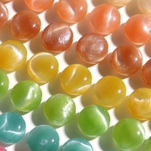 Macro detail of 15mm colorful glitter resin beads with cat eye effect for DIY crafts