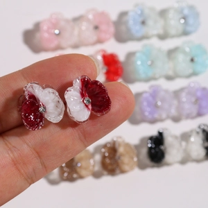 Handheld view of resin flower petal heart earrings with crystal center in multiple colors