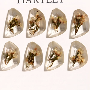 Detailed view of eight multifaceted resin pendants with embedded dried flowers for DIY