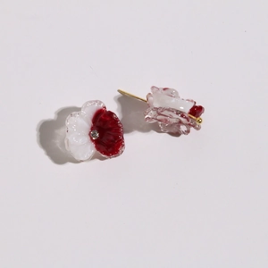 Macro view of red and white resin flower petal earrings with a crystal center and gold pin